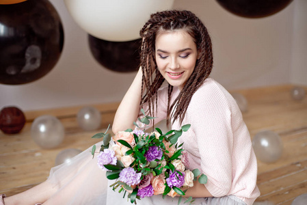 微笑的少女与辫子的发型捧着一束鲜花的手在室内