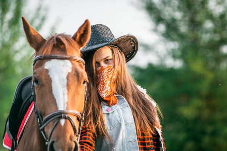 女牛仔帽子站附近一匹马在一个字段中