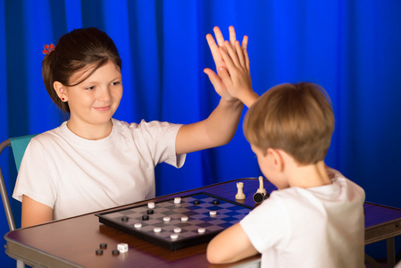 儿童男孩和女孩玩棋盘游戏叫跳棋