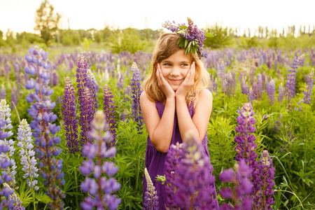 美丽的女孩微笑着紫色的礼服与花圈的 lupines。夏季开花 lupines 场