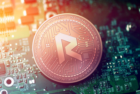 闪亮的铜 Revain cryptocurrency 硬币在模糊的主板背景上