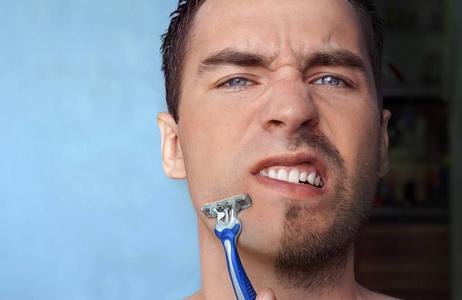 男人刮胡子不加奶油或泡沫,他脸上的疼痛照片