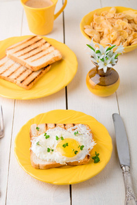 烤面包，鸡蛋黄板附近与花白色木制背景上的花瓶中。健康的早餐
