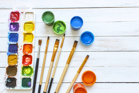 颜料和画笔在白色的木制背景照片