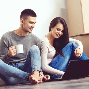 男人和女人用笔记本电脑和盒子。年轻夫妇用手提电脑浏览互联网。在一个新的家庭概念中移动