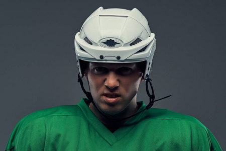 特写肖像的愤怒的职业曲棍球运动员在保护运动服和头盔。在灰色背景上隔离