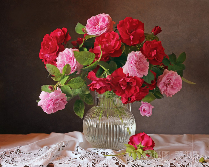 静物与粉红色和红色的玫瑰花,在一个透明的罐子