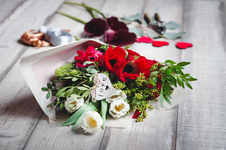 白色和红色的郁金香花束躺在一张小木桌上