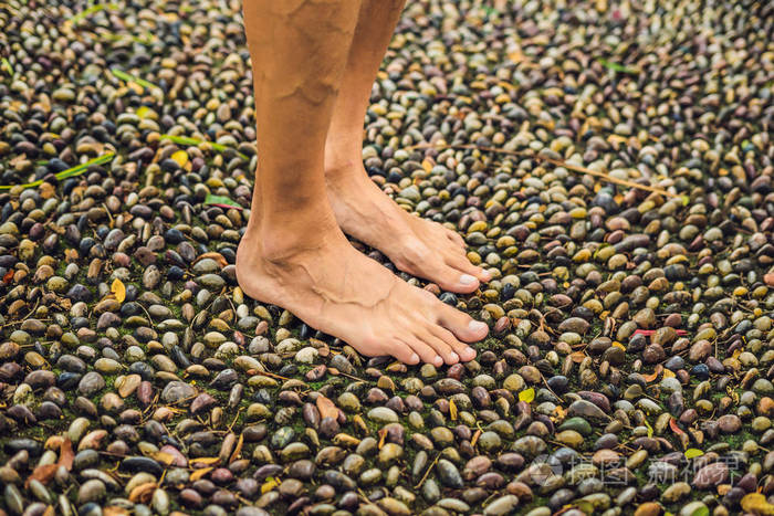 男子走在纹理鹅卵石路面, 按摩.脚底反射的路面卵石石