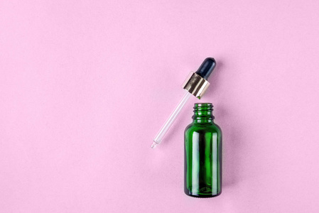 最低限度的皮肤护理照片, 化妆品包装。绿色玻璃瓶, 带有蜡笔色的吸管。平躺