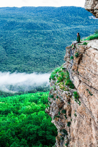坐在悬崖上欣赏风景的年轻人