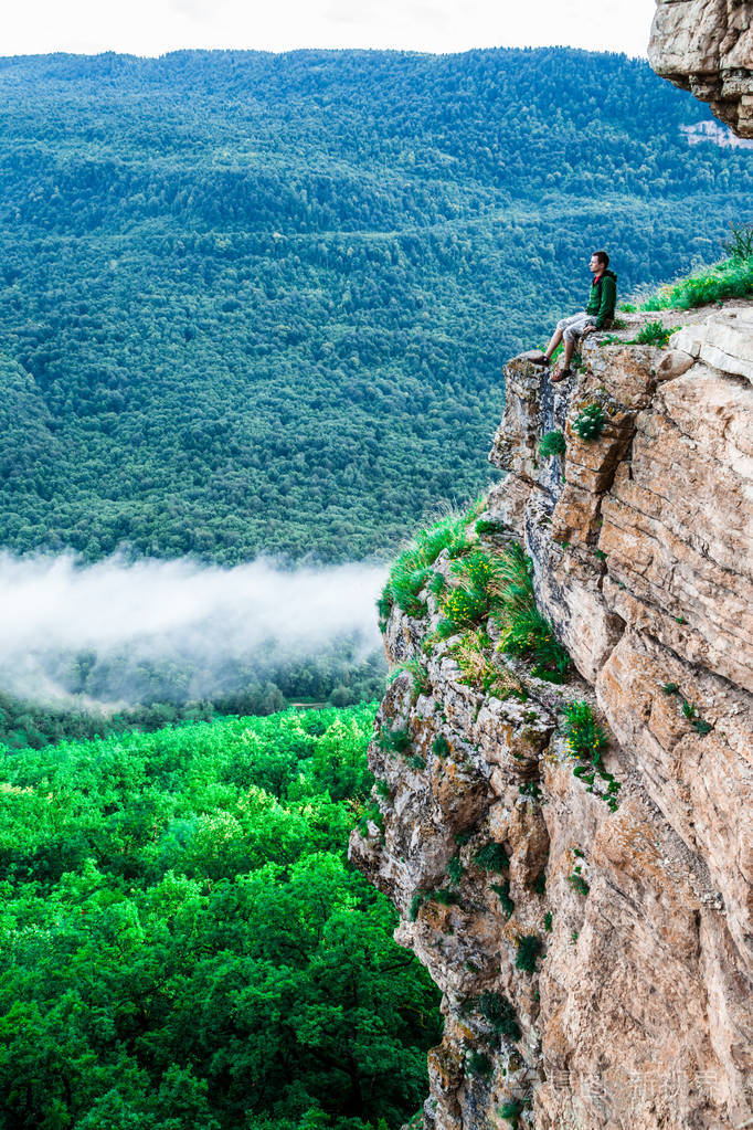 坐在悬崖上欣赏风景的年轻人