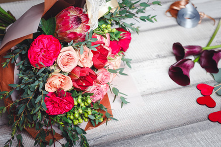 深粉色和红色的玫瑰花束躺在一张小木桌，空间为文本