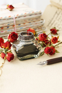 墨水池, 钢笔, 干玫瑰和一叠老式字母。复古风格
