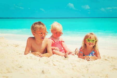 快乐的孩子小男孩和女孩玩沙滩上的沙子