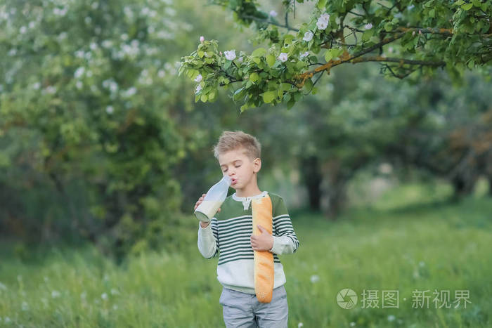 小男孩在花园里喝牛奶和吃面包