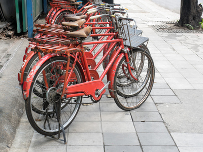 许多人在人行道上停车的红色经典自行车