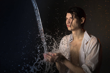 在湿衣服和溅水的迷人的年轻男子的肖像.工作室照片照片