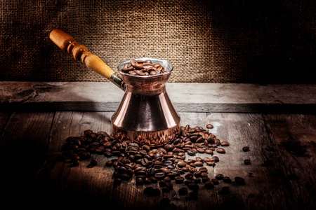 散落的咖啡豆和铜咖啡土耳其人在木质背景