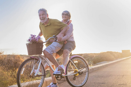快乐和幸福的成年夫妇开始和有乐趣旅行在同一辆自行车在户外活动与