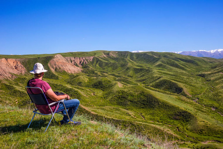 一个男人坐在椅子上检查周围的风景。哈萨克斯坦