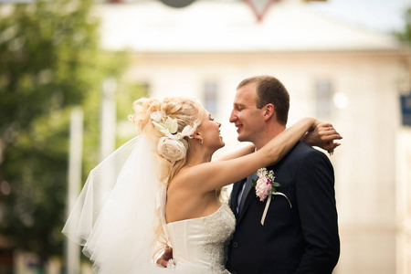 幸福的新娘，与巨大的花在她的头发抱着新郎的脖子