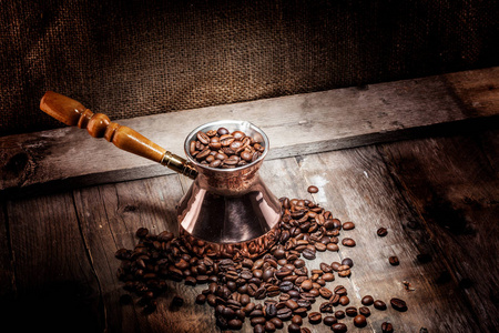 散落的咖啡豆和铜咖啡土耳其人在木质背景