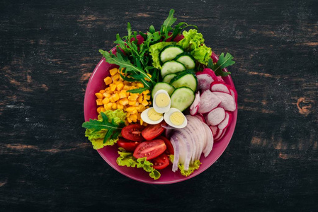 新鲜蔬菜沙拉。玉米, 萝卜, 洋葱, 黄瓜, 鹌鹑蛋。在一个木质的背景。顶部视图。自由复制空间