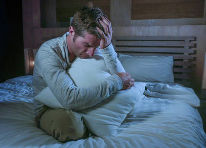 年轻的悲伤和绝望的人醒着深夜在床上在黑暗中遭受压抑和焦虑寻找压力