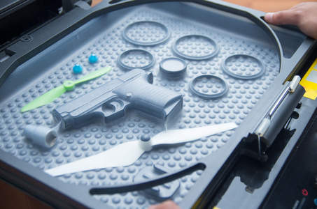 黑色橡胶圈 玩具枪 小螺旋桨躺在塑料泡沫表面，打印屏幕进程