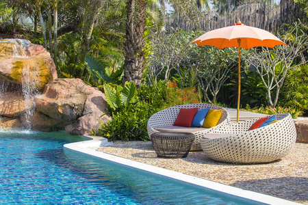 热带海滩与游泳池椰子棕榈树藤沙发床和伞在海附近, 泰国
