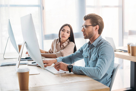 在办公室工作的跨种族商业同事的侧面视图外国人在不明飞行物飞在图书