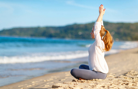 女人练瑜伽和冥想在荷花的立场上海滩