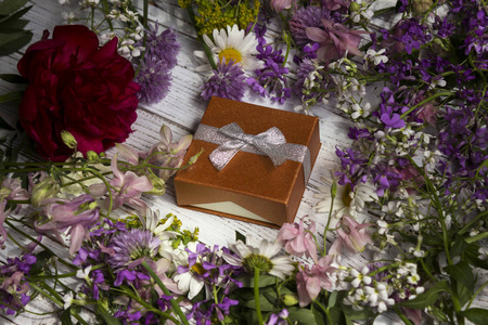 一个装在纸板箱里的礼物, 周围有许多粉红色丁香花和红花。节日礼物