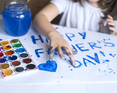 制作自制贺卡的孩子。手绘的手。一个小女孩在一张自制贺卡上画了一颗心, 作为父亲节的礼物。手指油漆。传统的戏剧概念。艺术与工艺概念