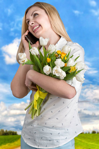 在移动电话上交谈的白色郁金香花束的年轻妇女。春 妇女节 母亲节这一天