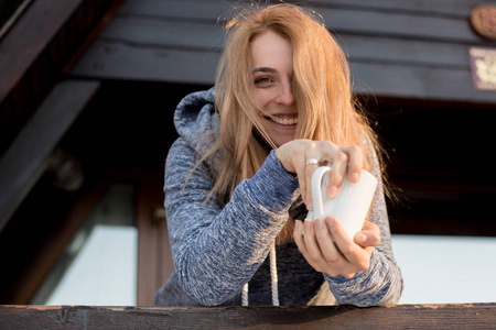 美丽的女人与白色的杯子站在阳台上的木房子和微笑