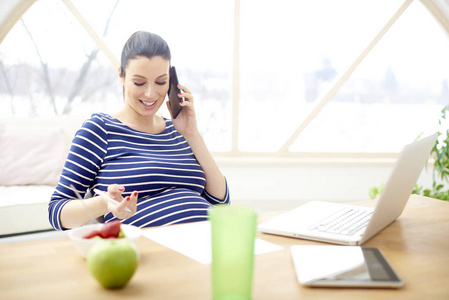 快乐的年轻孕妇交谈时, 坐在办公桌前的笔记本电脑