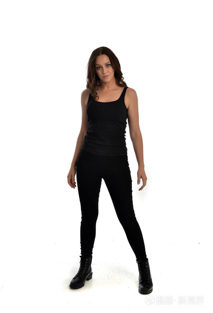 穿着黑色单线, 牛仔裤和靴子的黑发女孩的全长肖像.站立的姿态, 被隔