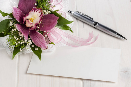 空白白卡上白色的木桌旁边兰花和银圆珠笔