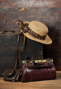 旧的木制手提箱, 妇女的草帽, 复古相机和旅行袋在黑暗的垃圾背景。旅行的概念