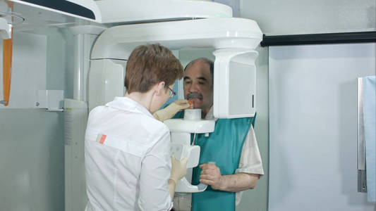 医生或放射科帮助老人做电脑分析牙齿