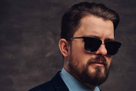 和发型身着优雅的正式西装和太阳镜在一个纹理深色背景在演播室照片