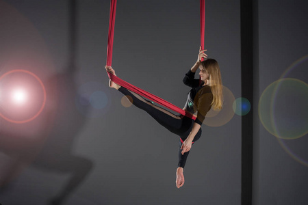 飞瑜伽。年轻女子练习空中反重力瑜伽与吊床在健身俱乐部的灰色背景
