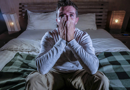 年轻的悲伤和绝望的男人躺在床上哭泣,沮丧地看着,深思熟虑的痛苦