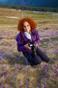 妇女游人用照相机在牧场用番红花花在山里