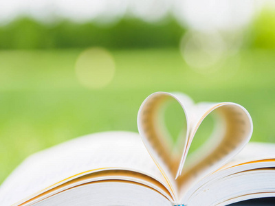 在顶一个打开与页成型的心形状的花园里的桌子上的书照片