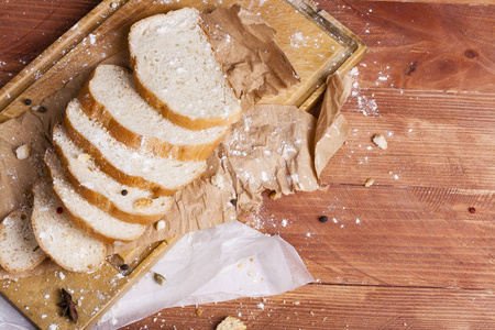新鲜和芬芳的白面包切片和躺在一个木质的背景。一个小香料已经添加到它, 它也位于牛皮纸。无麸质。概念性食品照片