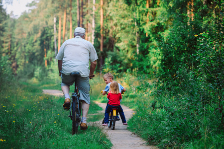 活力的老人骑着自行车在自然的孙子孙女