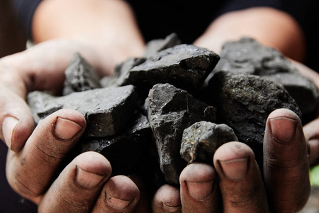 煤矿矿工在人手中的煤炭背景。煤炭开采或能源环保。工业煤。火山岩